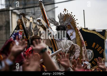 Philippinisch-katholische Anhänger heben ihre Hände und Handtücher, während Priester vor dem Fest des Schwarzen Nazareners in Manila, Philippinen, Heiliges Wasser auf die Repliken des Schwarzen Nazareners streuen. Stockfoto