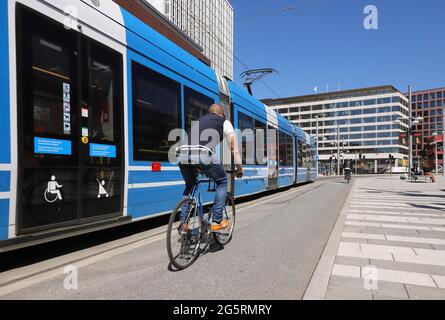 Stockholm, Schweden - 12. Mai 2021: Ein Mann fährt im Zentrum Stockholms neben einer modernen Straßenbahn der Linie 7 am Sergels Torg Platz. Stockfoto