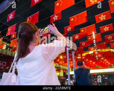 Hongkong, China. Juni 2021. Eine Frau fotografiert die Nationalflaggen Chinas und die Flaggen der Sonderverwaltungsregion Hongkong anlässlich des 24. Jahrestages der Rückkehr Hongkongs nach China. Hongkong feiert am 1. Juli den Jahrestag der Rückkehr nach China mit einer Flagge in Tsim Sha Tsui. In diesem Jahr ist der 1. Juli auch der gleiche Tag für die Feierlichkeiten zum 100. Jahrestag der Kommunistischen Partei Chinas in Peking. Kredit: SOPA Images Limited/Alamy Live Nachrichten Stockfoto