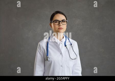 Porträt einer selbstbewussten, seriöse junge Ärztin auf grauem Beton-Hintergrund. Stockfoto