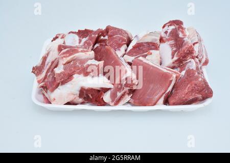 Gehackte Lammrippen auf einem Teller auf weißem Hintergrund, rohes Fleisch vom Hammelfleisch, geschnitten Stockfoto