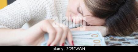 Junge Frau, die auf Geldhaufen liegt und Dollar hält In ihren Händen Stockfoto