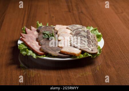 Fleischdelikatessen Schneiden, Aufschnitt, Rindfleisch, geräucherter truthahn, Pferdefleisch auf einem weißen Teller auf dem Tisch Stockfoto