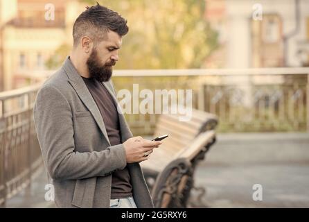 Vielbeschäftigter Hipster erhielt Nachricht per E-Mail im Smartphone über mobiles Internet im Freien, E-Mail Stockfoto