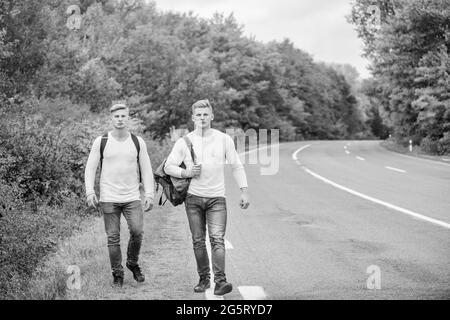 Freunde des Unternehmens Reisende, die auf der Straße Natur Hintergrund trampen. Gehen Sie in die Nähe des Stadtrandes. Reisende unterwegs. Freunde, die Wanderer auf Reisen halten. Beginnen Stockfoto