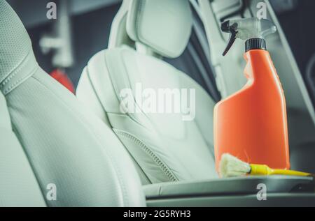 Waschmittel für Leder im Innenraum des Autos in orangefarbener Flasche. Thema Fahrzeugwartung. Stockfoto