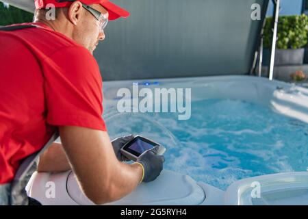 Kaukasischer Garten SPA Techniker in seinen 40er Jahren Testen Whirlpool Remote in SPA Pavillons. Stockfoto