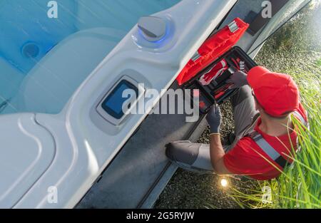 Jacuzzi Professionelle SPA Techniker repariert die Pumpelemente im Whirlpool. Kaukasischer Arbeiter in den 40er Jahren. Draufsicht. Stockfoto