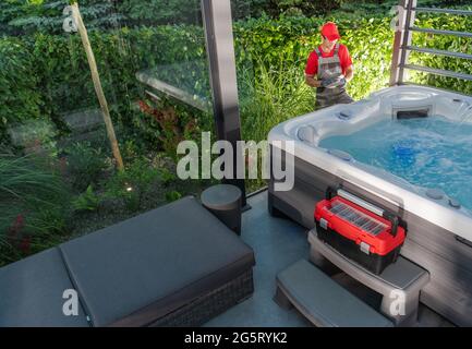 Spa-Techniker in den 40er Jahren, der den Whirlpool durchführt, prüft direkt nach der Installation in Garten-SPA-Pavillons. Moderne Architektur Jacuzzi Shelter Stockfoto