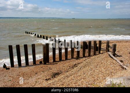 An einem Kiesstrand an der Südküste Englands in der Nähe von Warsash und Titchfield befinden sich Erosionsgroynes und Verzierungen an der Küste Stockfoto