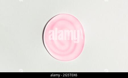Rosa transparente Gel-Tropfen isoliert auf weißem Hintergrund. Draufsicht. Virenschutz- oder Kosmetikkonzept. Nahaufnahme der Serumtextur Stockfoto