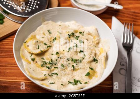 Ravioli mit Pilzen, Parmigiano, Petersilie und frischem Basilikum. Holztisch-Anordnung. Nahaufnahme Stockfoto