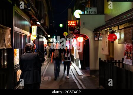 Kyoto, Japan - 16. April 2019: Menschen, die in dunkler Nacht auf der engen Straße des Pontocho-Gassenviertels spazieren, mit beleuchteten Laternen und Izakaya-Restaurants Stockfoto