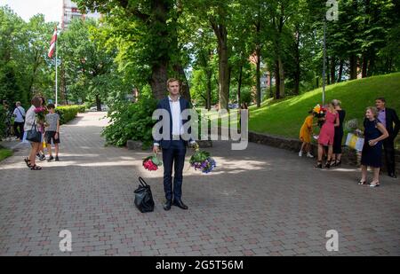 Riga, Lettland. Juni 2021. Am 29. Juni 2021 warten Menschen mit Blumensträußen auf Studenten, die an einer Abschlussfeier vor der Rigaer Stradins-Universität in Riga, Lettland, teilnehmen. Quelle: Edijs Palens/Xinhua/Alamy Live News Stockfoto