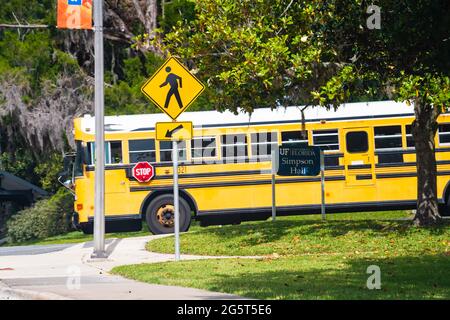 Gainesville, USA - 27. April 2018: Straßenschulbus in der Innenstadt von Florida mit UF-Campus-Schild der University of Florida für die Simpson Hall Stockfoto