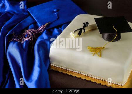 Blaues Abschlusskleid und Mütze mit Kuchen für Schulende. Stockfoto