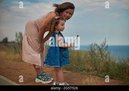 Frau und Kind stehen auf einer Wiese mit Blick auf das Meer Stockfoto