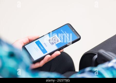 Impfpass, Reisender Mann mit Gesundheitspass der Impfpass-Zertifizierung auf Smartphone-App am Flughafen vor dem Einsteigen in das Flugzeug während der coro Stockfoto