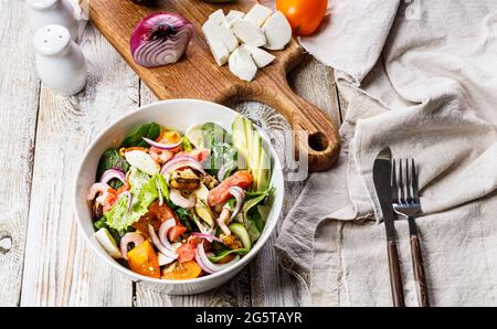 Köstlicher und gesunder mediterraner Sommersalat. Muscheln, Garnelen, Lachs, Tomaten, Eissalat, Avocado, rote Zwiebeln, Gewürze und Olivenöl. Gourmet-sti Stockfoto