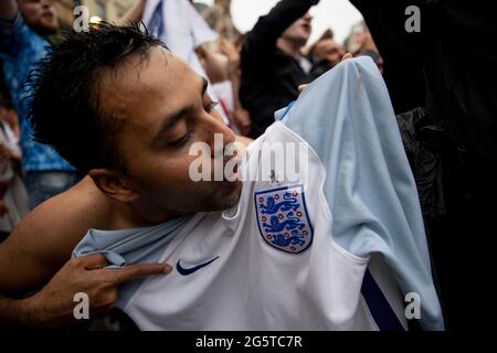 London, Großbritannien. Juni 2021. Ein leidenschaftlicher Fußballfan küsst das England-Logo auf sein Fußballtrikot.Hunderte von englischen Fußballfans versammeln sich und feiern heute Abend den Sieg von 2:0 über Deutschland in der Runde der 16. UEFA Euro 2020. Sie singen „Football is coming Home“ und freuen sich auf das Viertelfinale gegen Schweden oder die Ukraine an diesem Samstag. (Foto von Hesther Ng/SOPA Images/Sipa USA) Quelle: SIPA USA/Alamy Live News Stockfoto