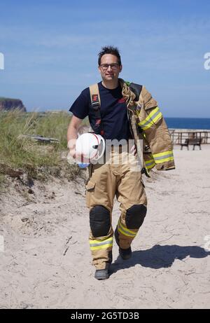 16. Juni 2021, Schleswig-Holstein, Helgoland: Felix Vorndran von der Freiwilligen Feuerwehr Bergisch-Gladbach steht während seines Dünendienstes auf der Düne der Tiefseeinsel Helgoland an der Feuerwache. Feuerwehrleute aus ganz Deutschland können auf der Hochseeinsel Helgoland das angenehme mit dem Nützlichen während der Saison verbinden. Die Gemeinde sucht nach der Sicherung des Brandschutzes auf der Düne freiwillige Feuerwehrkameraden und -Genossen, die mit Ihrem Einsatz die touristische Nutzung der Düne aufrechterhalten. Die Feuerwehrmänner vom Festland sind in Bungalows auf untergebracht Stockfoto