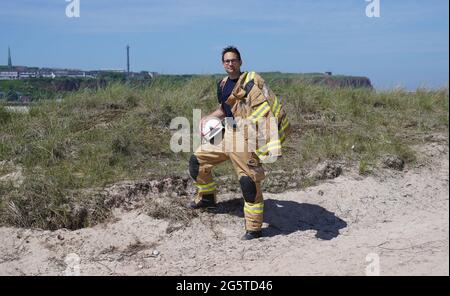 16. Juni 2021, Schleswig-Holstein, Helgoland: Felix Vorndran von der Freiwilligen Feuerwehr Bergisch-Gladbach steht während seines Dünendienstes auf der Düne der Tiefseeinsel Helgoland an der Feuerwache. Feuerwehrleute aus ganz Deutschland können auf der Hochseeinsel Helgoland das angenehme mit dem Nützlichen während der Saison verbinden. Die Gemeinde sucht nach der Sicherung des Brandschutzes auf der Düne freiwillige Feuerwehrkameraden und -Genossen, die mit Ihrem Einsatz die touristische Nutzung der Düne aufrechterhalten. Die Feuerwehrmänner vom Festland sind in Bungalows auf untergebracht Stockfoto