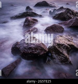 Felsen und fließende Wellen entlang der Küste von Camiguin Island Stockfoto