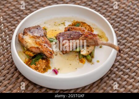 Frisch gegrilltes Lammsteak auf weißem Teller im Freiluftrestaurant am Sommertag Stockfoto