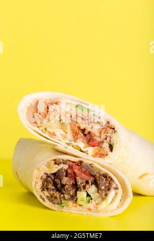 Dönerrolle Shawarma mit Huhn und Gemüse auf gelb Stockfoto
