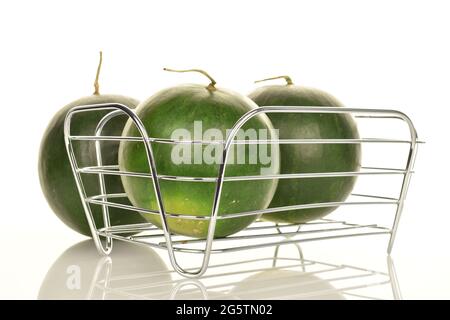Drei reife organische Wassermelonen mit einem Korb aus Metalldraht, Nahaufnahme, auf weißem Hintergrund. Stockfoto