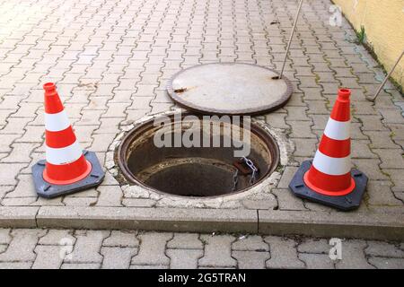 Das offene Mannloch ist mit Verkehrskegeln gesichert Stockfoto