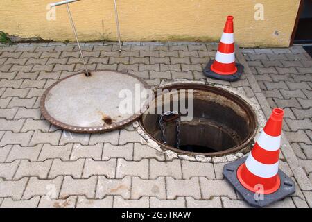 Das offene Mannloch ist mit Verkehrskegeln gesichert Stockfoto