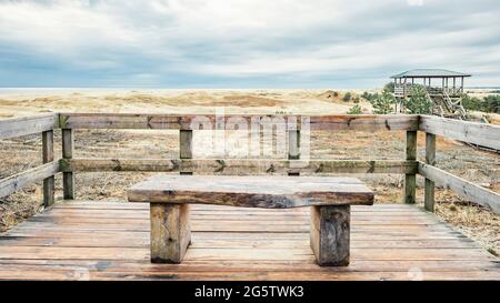 Eine Holzbank mit Blick auf die Sanddünen der Kurischen Lagune und der Kurischen Bucht Stockfoto
