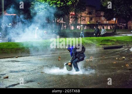 Bogota, Kolumbien. Juni 2021. Ein Protestler sah während der Demonstration, wie er einen Tränengaskanister lösch, indem er ihn mit einem Eimer bedeckte. Der 28. Juni markierte zwei Monate der Proteste in Kolumbien. In vielen Städten des Landes fanden Blockaden und Demonstrationen statt. Als Reaktion darauf setzte die Regierung eine Anti-Unruhen-Polizei ein und löste Zusammenstöße aus, bei denen Hunderte von Demonstranten verletzt wurden. Kredit: SOPA Images Limited/Alamy Live Nachrichten Stockfoto