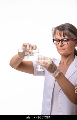 Frau in einem Labormantel, die Flüssigkeit in einen Laborkolben gießt Stockfoto