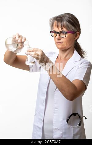 Frau in einem Labormantel, die Flüssigkeit in einen Laborkolben gießt Stockfoto