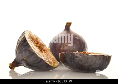 Eine ganze und zwei Hälften dunkelvioletter Feigen, aus der Nähe, isoliert auf weißem Hintergrund. Stockfoto