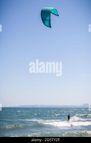 In Empuriabrava, Costa Brava, Provinz Girona, Katalonien, Spanien, wird ein Kiteboarder bei starkem Onshore-Wind von einem Starkdrachen über das Wasser gezogen. Kiteb Stockfoto