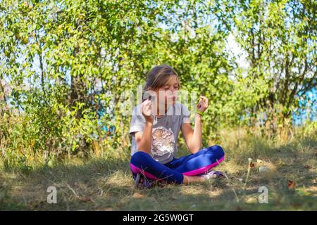 Defocus caucasian preteen Mädchen praktiziert Yoga im Park, Wald, im Freien, draußen. Meditation und Konzentration. Wellness gesunder Lebensstil. Yoga-Mädchen Stockfoto