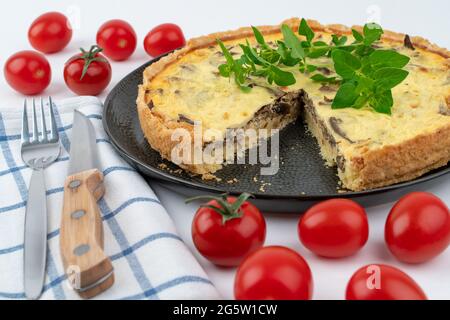 Nahaufnahme breite Studio-Aufnahme von frisch gebackenen gelben Französisch salzigen Kuchen, oder Quiche mit Pilzen, rote Kirschtomaten, grüne Minze und Küchentuch, auf BL Stockfoto