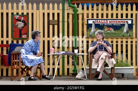 Zwei ältere Frauen in der Kleidung der 1940er Jahre auf dem Bahnhof von Alresford während der jährlichen Veranstaltung „war on the Line“ in Alresford, Hampshire, Großbritannien. 13. Juni 2021. Stockfoto