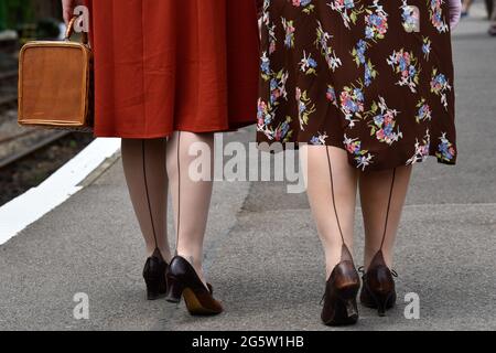 Zwei Frauen in den 1940er Jahren kleiden sich während des jährlichen „war on the Line“-Events in Alresford, Hampshire, Großbritannien, am Bahnhofsplatz entlang. Stockfoto