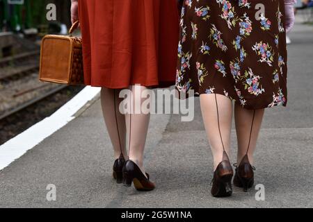 Zwei Frauen in den 1940er Jahren kleiden sich während des jährlichen „war on the Line“-Events in Alresford, Hampshire, Großbritannien, am Bahnhofsplatz entlang. Stockfoto