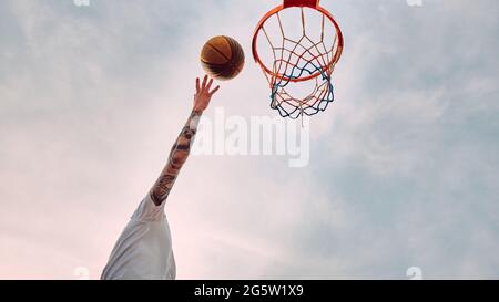 Die Hand wirft Basketball auf den Reifen Stockfoto