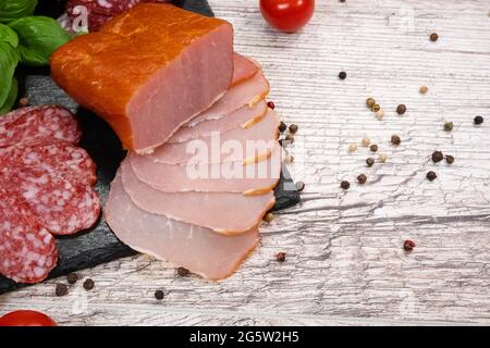 Schneiden von verschiedenen Arten von geräucherter Wurst und Fleisch auf einem hölzernen Hintergrund. Draufsicht Stockfoto