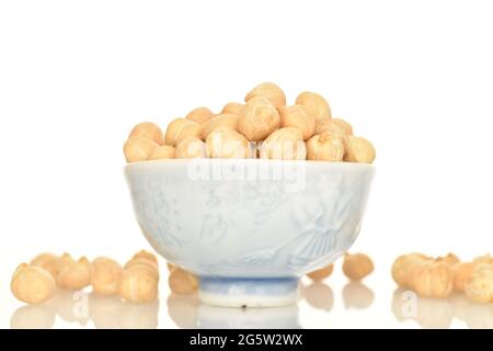 Organische, ungekochte Kichererbsen in einer Keramikschale, aus der Nähe, isoliert auf Weiß. Stockfoto