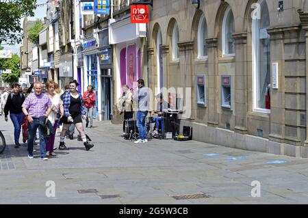 LANCASTER. LANCASHIRE. ENGLAND. 06-12-21. Ein Trio von Musikern, die auf der Penny Street im Stadtzentrum für die vorbeiziehenden Massen buscheln. Stockfoto