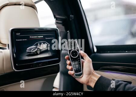 Ein Mann, der eine Multimedia-Fernbedienung in einem Auto hält Stockfoto