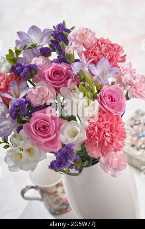 Vase mit pastellfarbenen Blumen auf einem Couchtisch in der Zimmereinrichtung Stockfoto