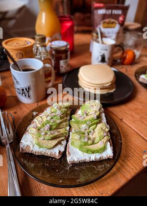 Hausgemachter Brunch mit Avocado-Toast und Pfannkuchen Stockfoto